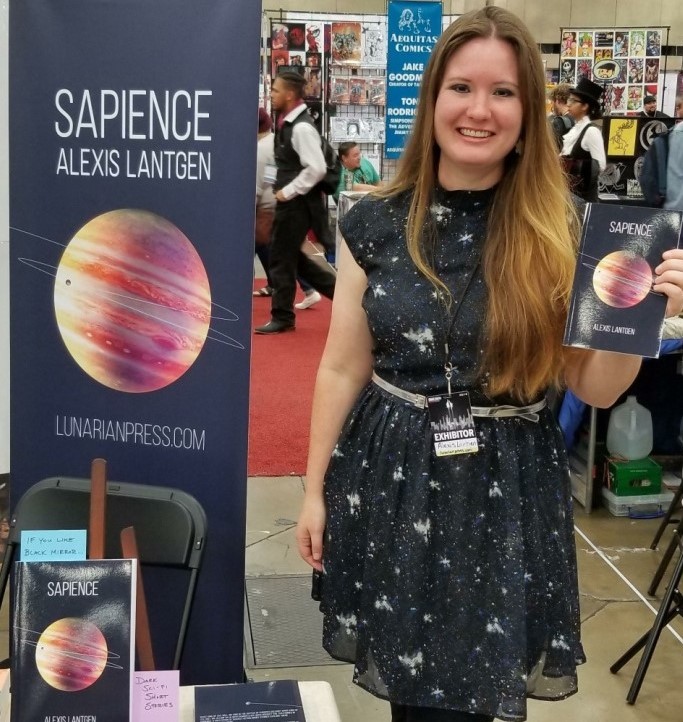 Author Alexis Lantgen holding her book, Sapience, by her author table at Dallas Fan Expo 2019